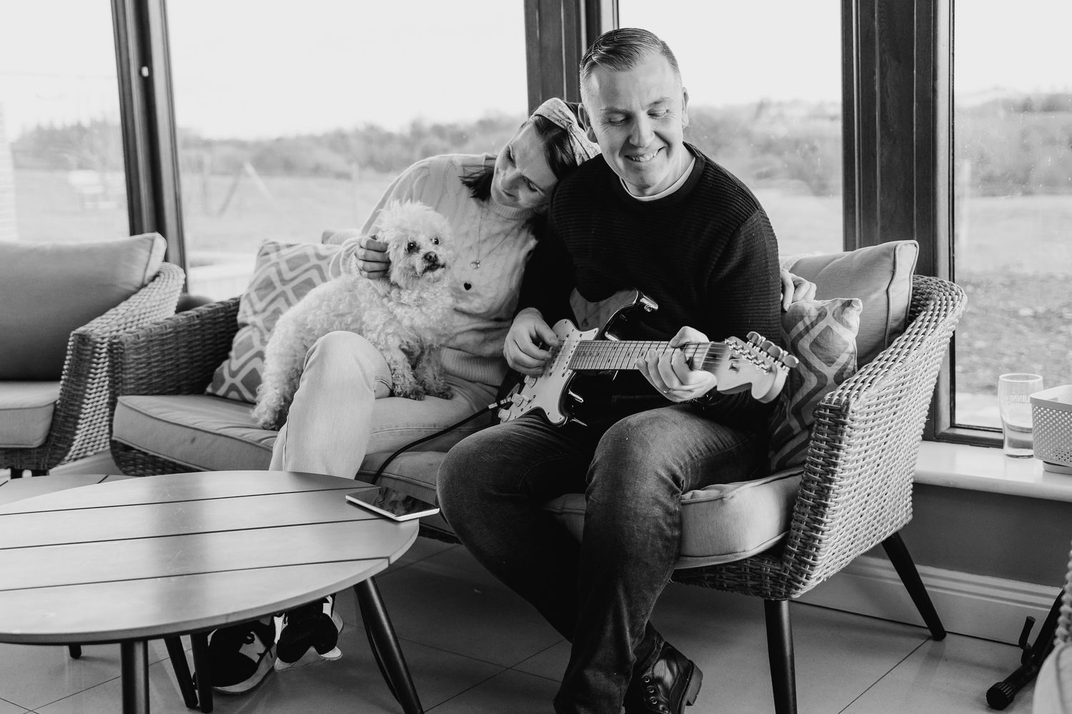 Black and white photo of person relaxing in armchair with two dogs in modern living room interior. PHOTOGRAPHER Dublin ireland