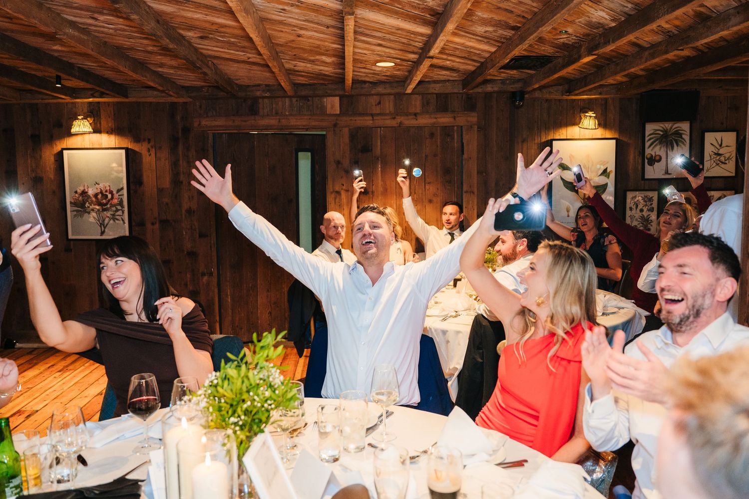 Wedding reception party with exposed wooden beams and warm lighting creates festive atmosphere. The Dean Dublin Wedding Photographer