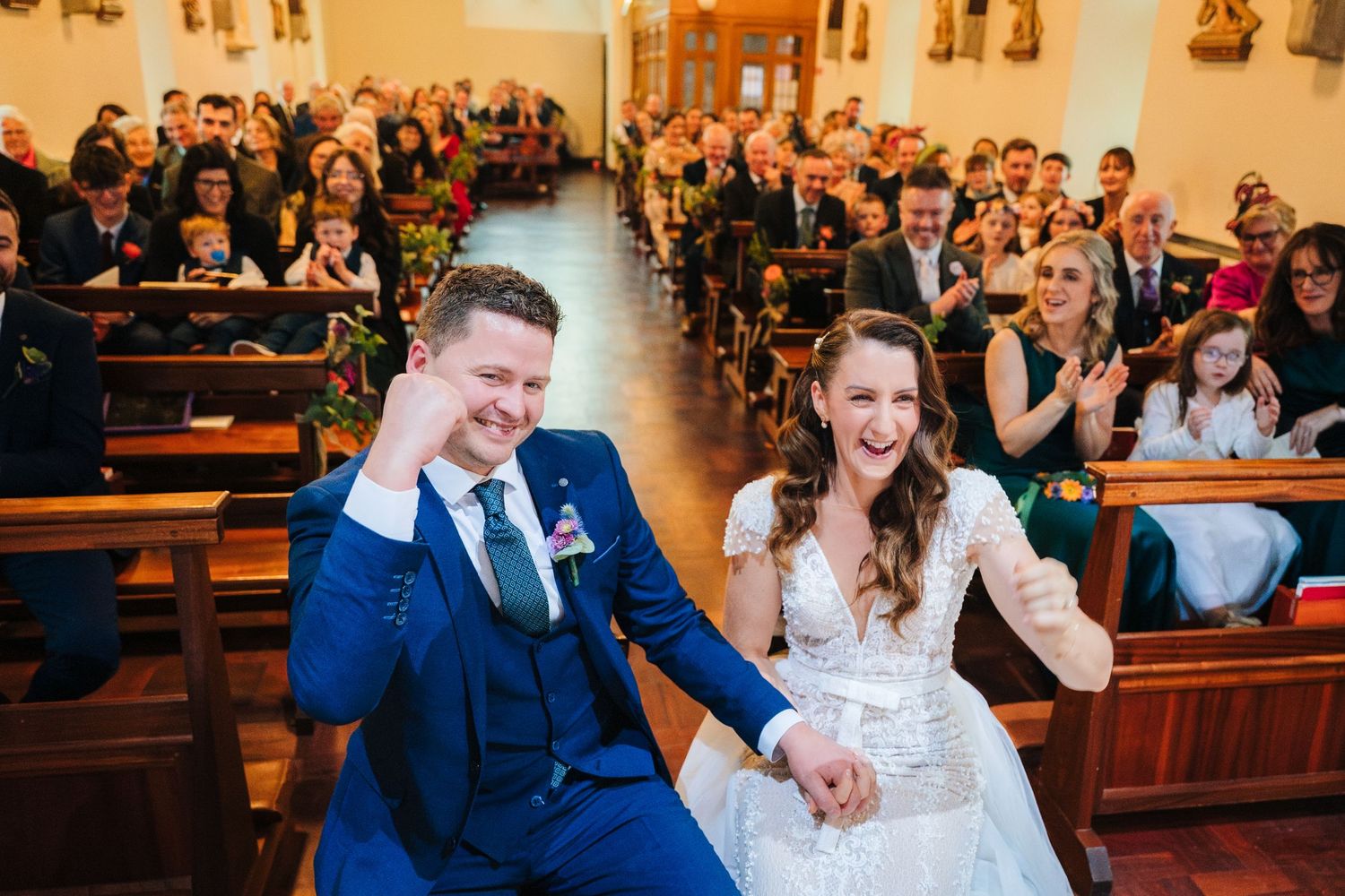 Wedding guests fill church pews during a joyous ceremony celebration.