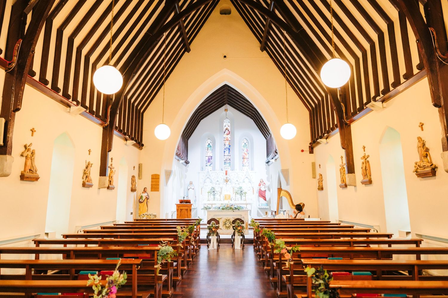 Interior of a traditional church with wooden beams and stained glass windows during a ceremony.