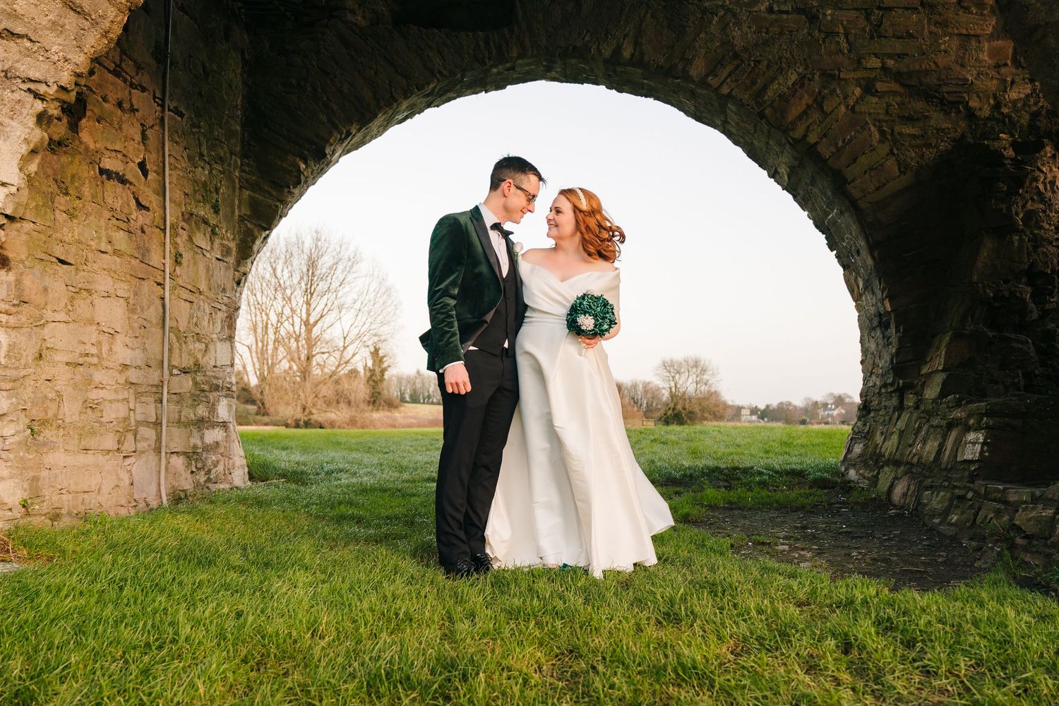 A sequence of romantic wedding portraits captured under stone archways surrounded by green grass and natural scenery. wedding photographer d
