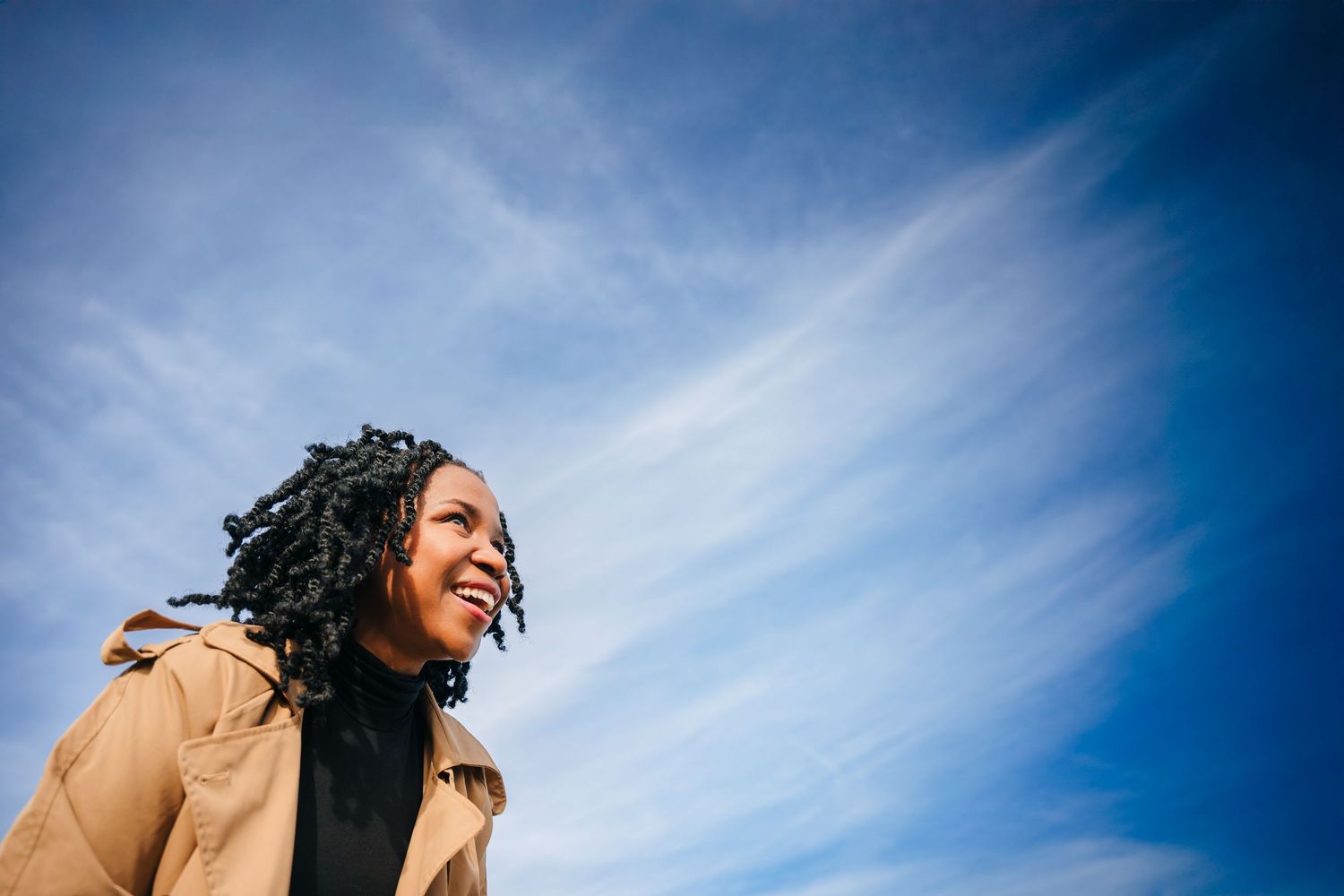 Upward angle shot of person against bright blue sky with wispy white clouds. Dublin professional headshots photographer