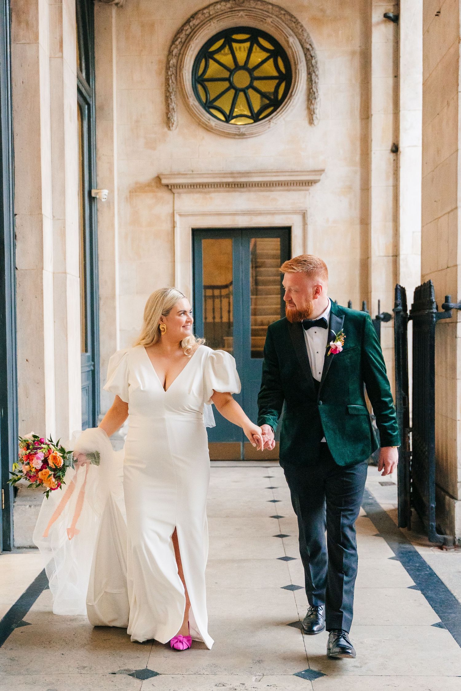 Wedding party posing under elegant stone archways with bright floral bouquets and formal attire. Wedding photographer dublin