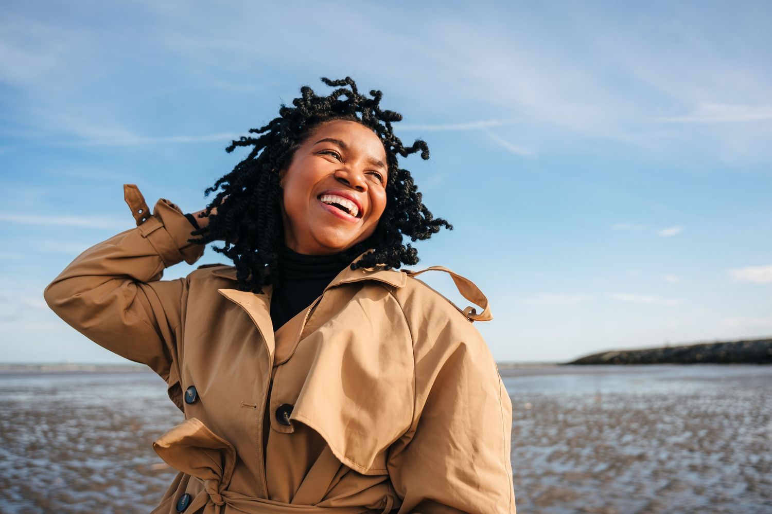 Person in a tan coat enjoys a bright sunny day against a blue sky background. Dublin professional headshot photographer
