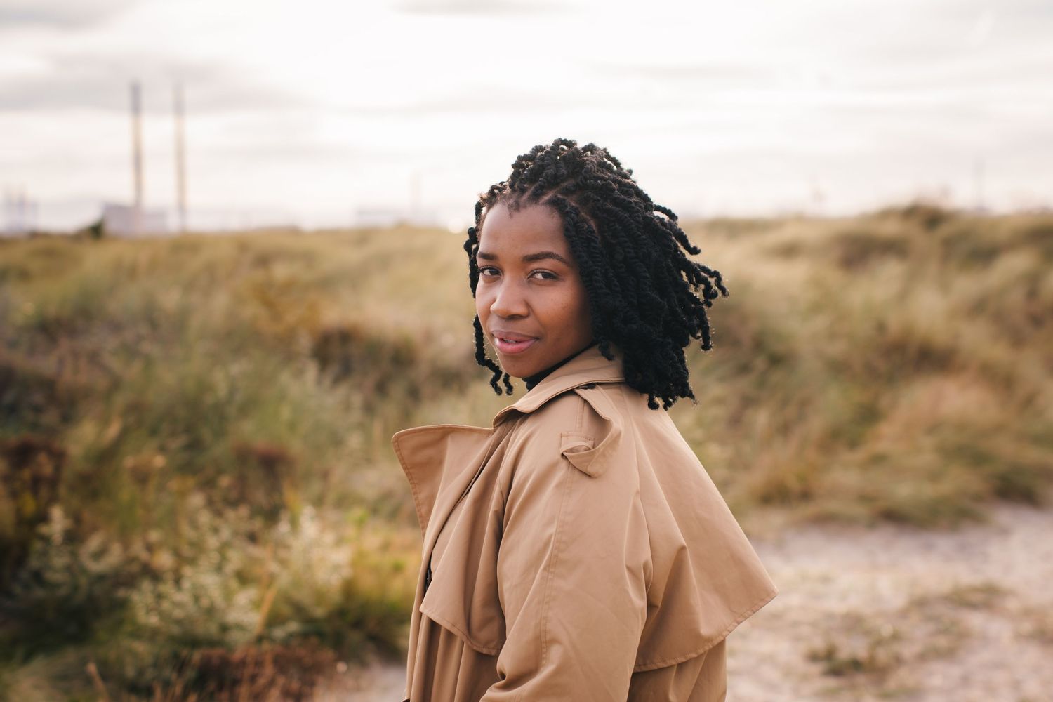 Artistic portrait series in natural coastal setting with tan coat and grass. Dublin professional headshots photographer