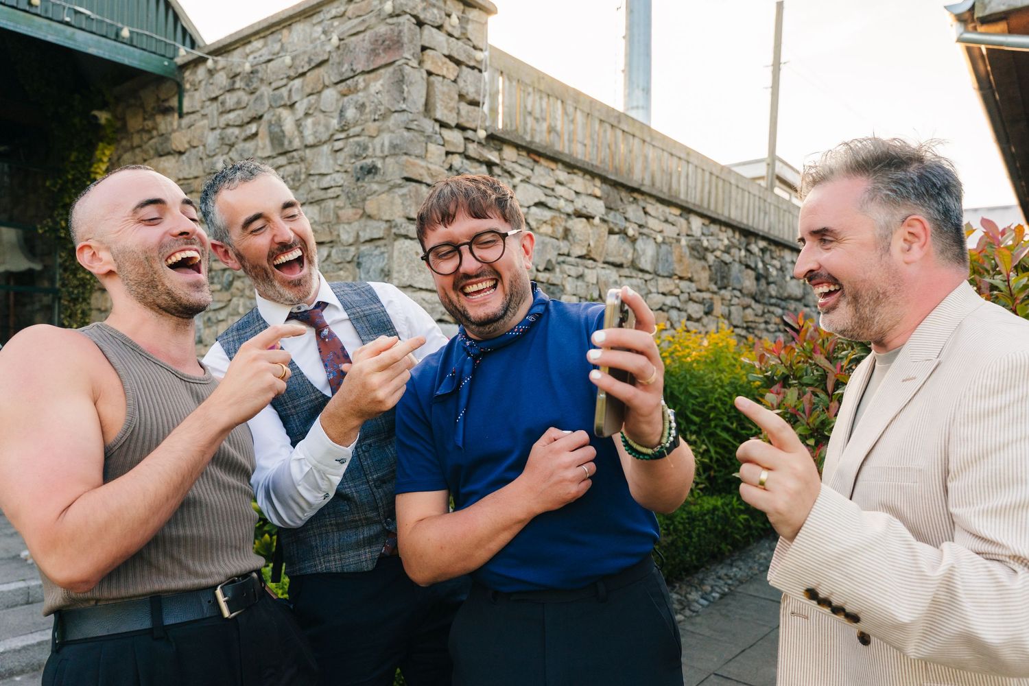 Wedding guests share laughter and drinks during an outdoor celebration at a stone venue. Wedding photographer dublin
