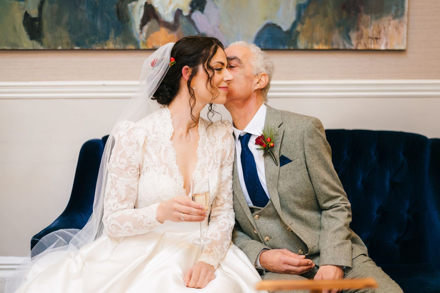 A couple in wedding attire share intimate moments while seated on a blue couch Stephens green club dublin Wedding photographer