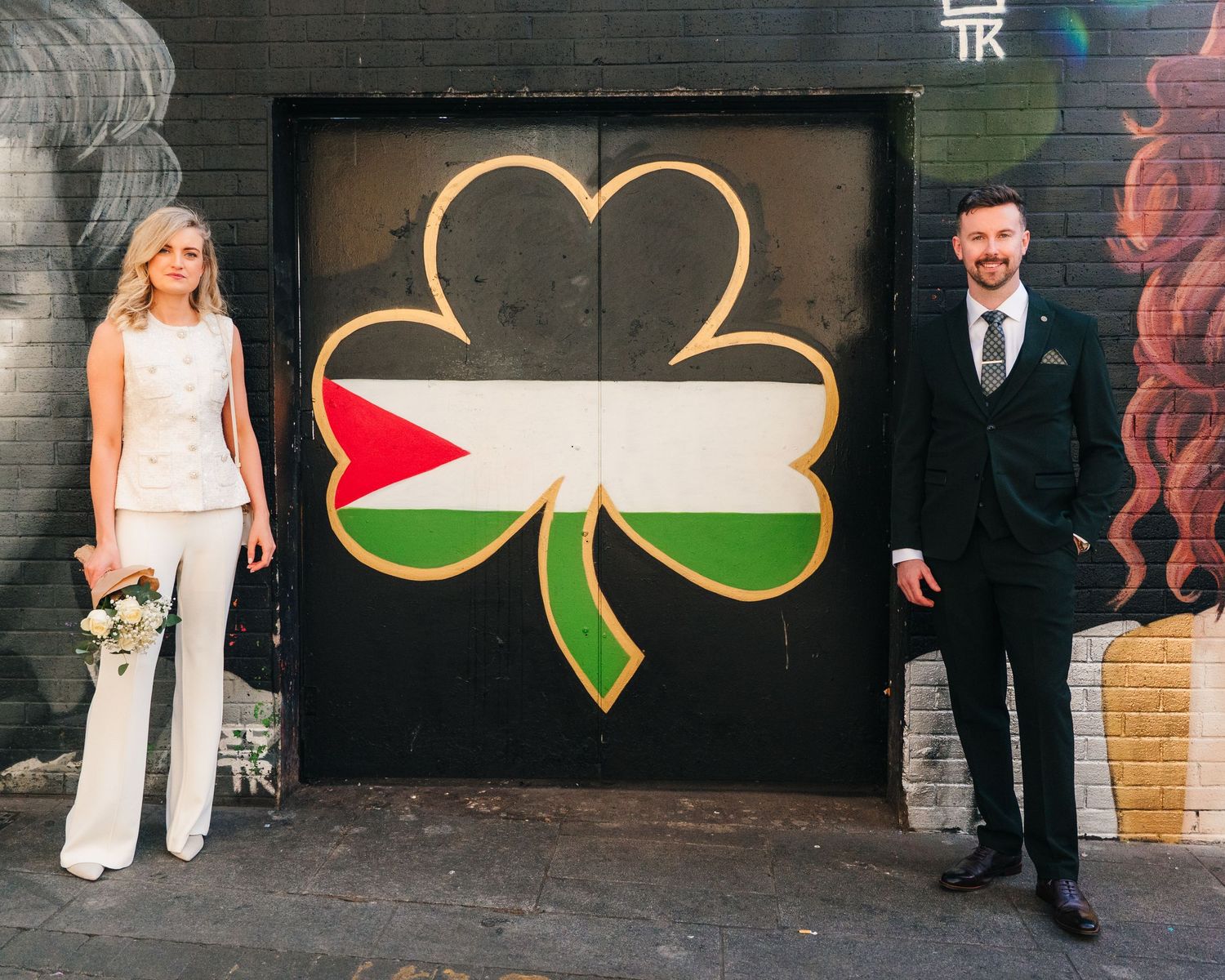 Urban art mural with shamrock designs creates backdrop for street photography in Dublin. City Hall Dublin wedding photogrAPher