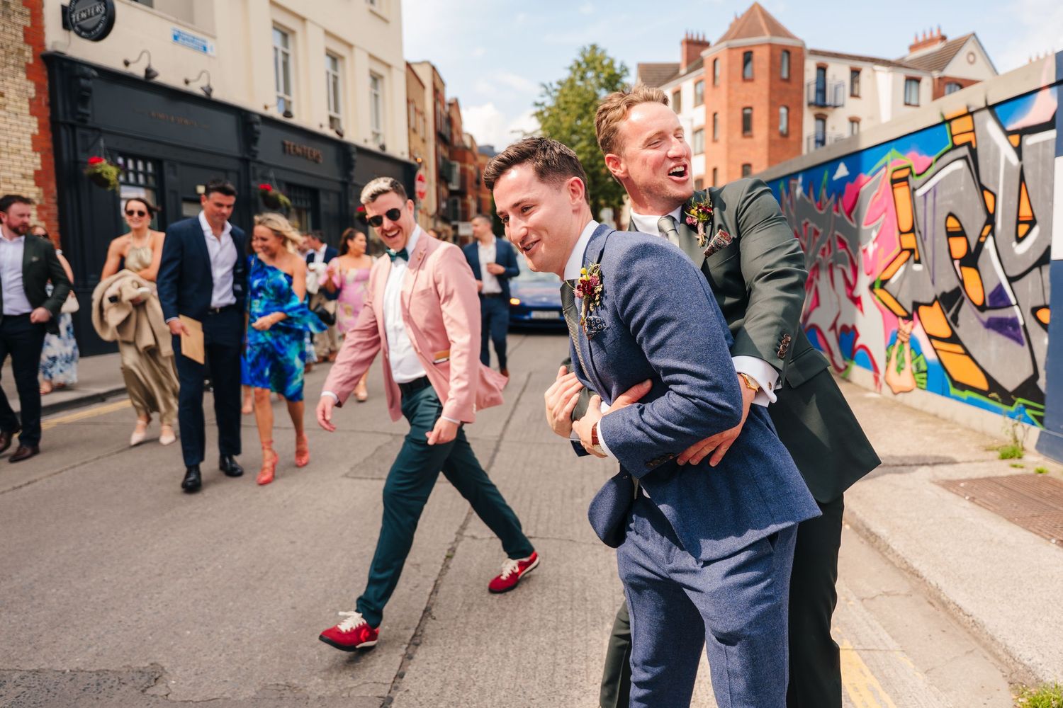 Party guests enjoying themselves in an urban outdoor setting with colorful walls. Same sex wedding PHOTOGRAPHER Dublin