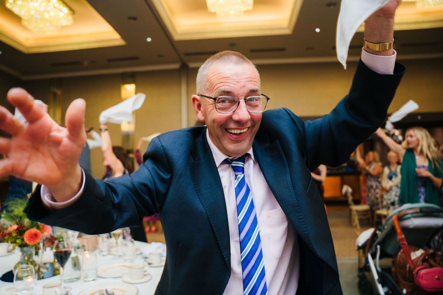 Wedding guest in blue striped tie celebrating enthusiastically at reception dinner.Wedding Photography Trim Castle Ireland