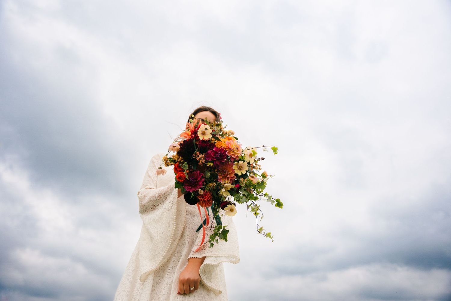 Outdoor wedding scene with cloudy skies and vibrant red floral bouquet. Wedding Photography Trim Castle Ireland