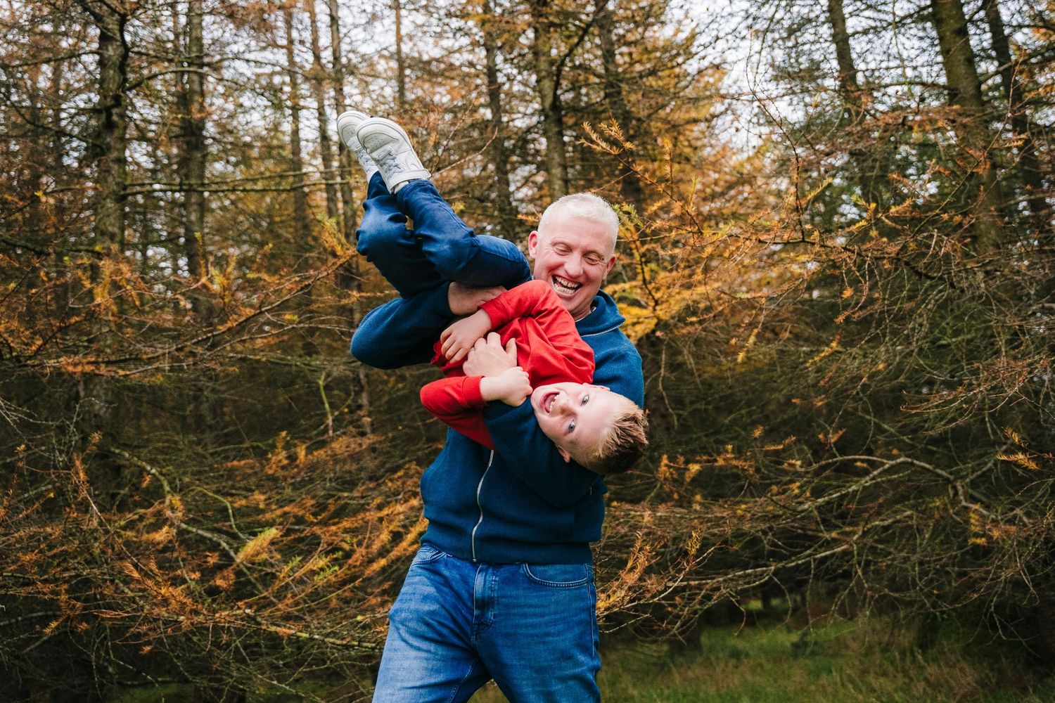 Family Photographer Dublin Ireland Candid family interactions and embraces among fall foliage in a forest setting.