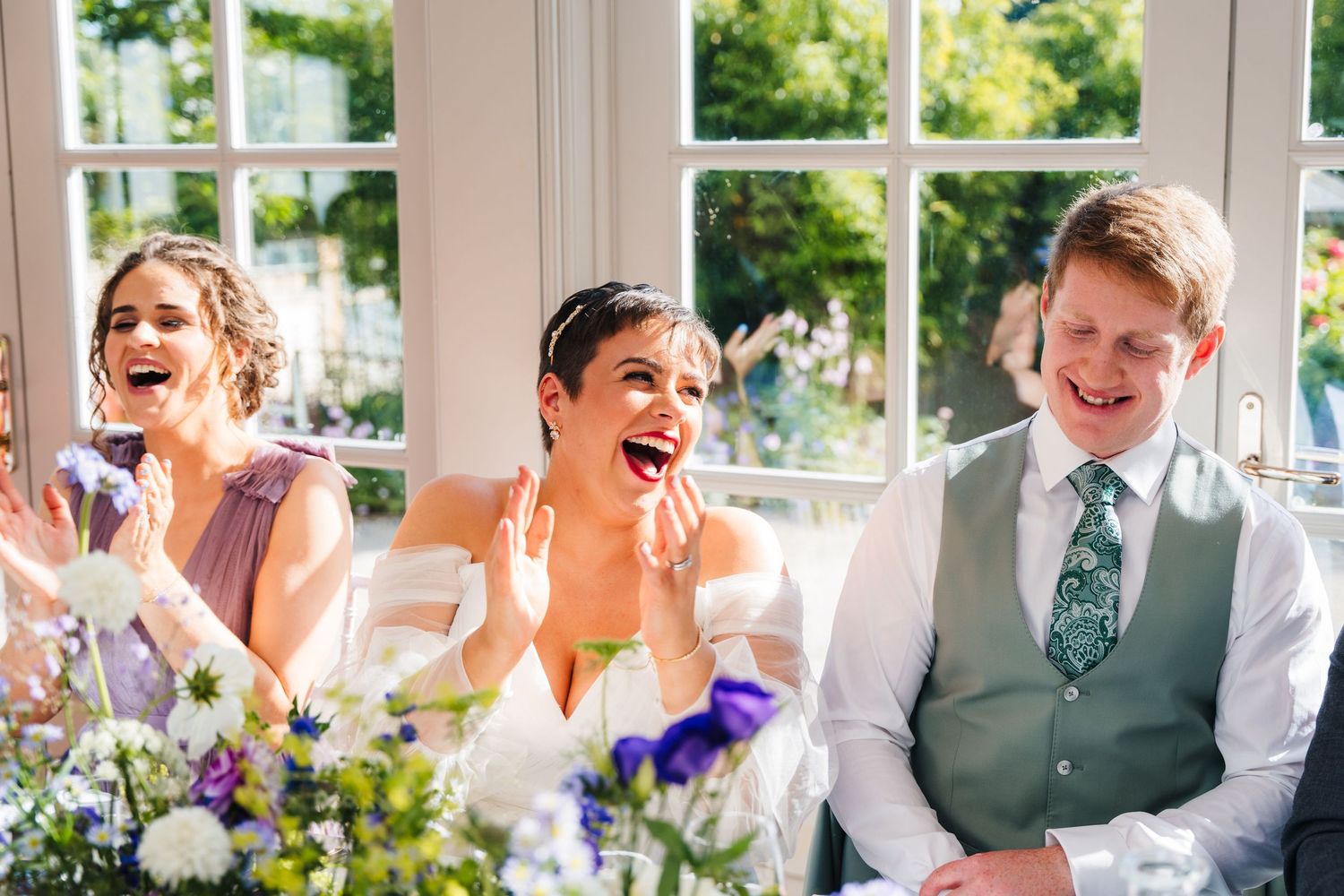 Millhouse slane wedding photographer dublin Wedding guests enjoying a reception in a sunlit room with large windows.