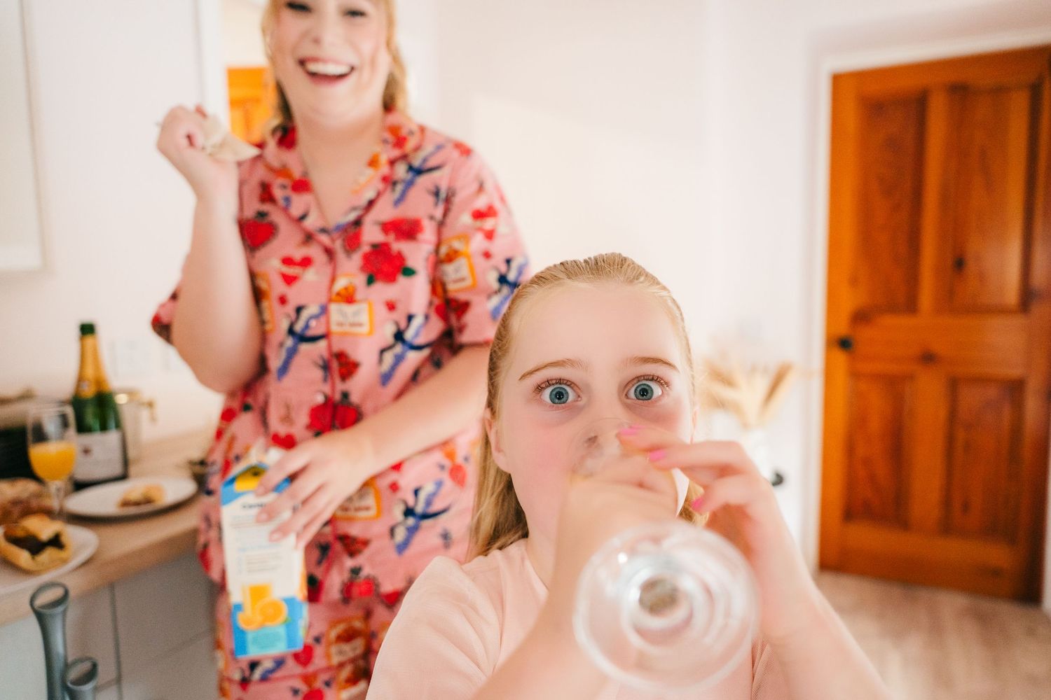 A playful scene in a kitchen shows someone in a floral top while another blows bubbles. . Village Barn Tyrrellspass wedding photographer Ire