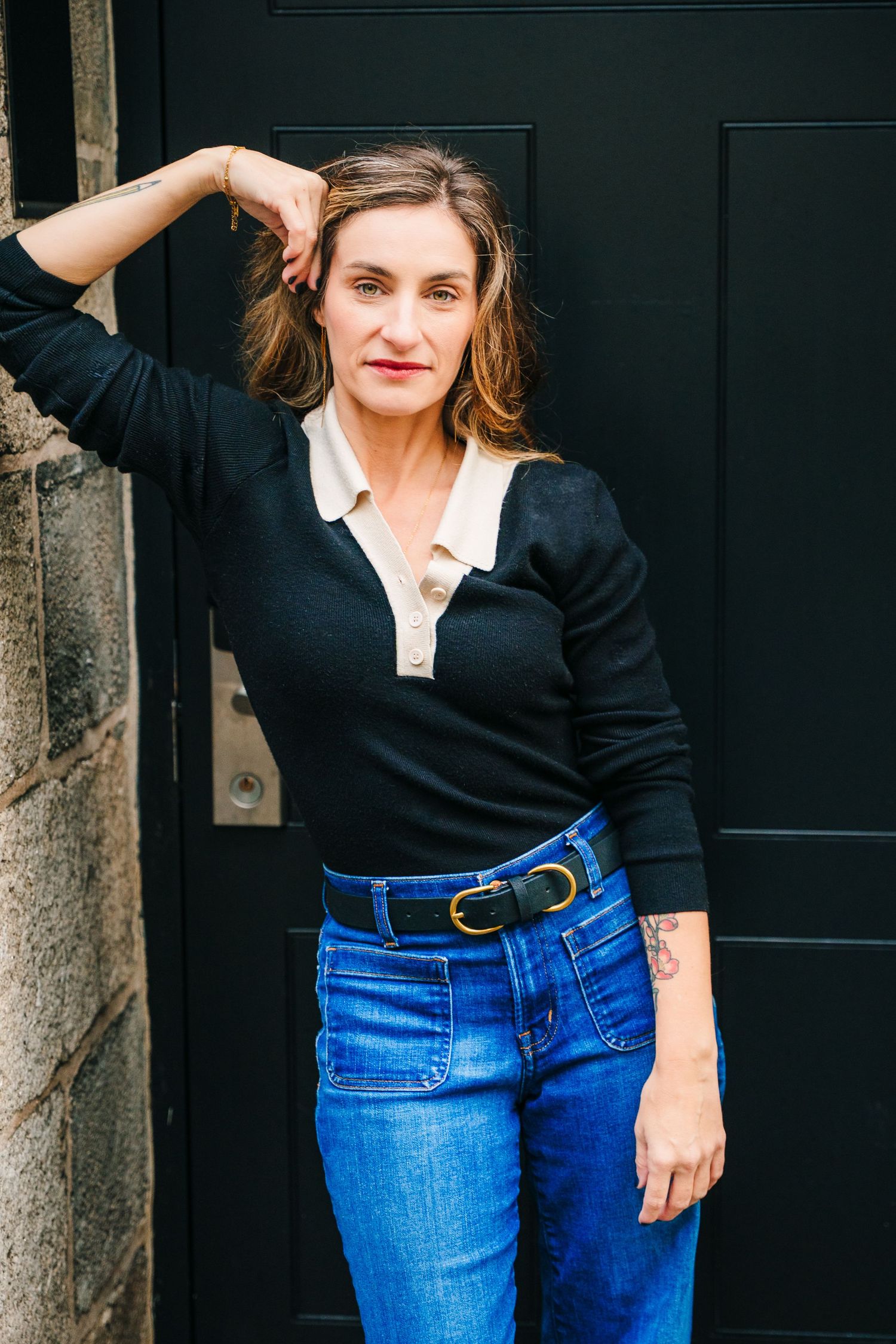 A casual outfit featuring blue jeans and a black v-neck top against a dark background. professional headshots dublin photographer