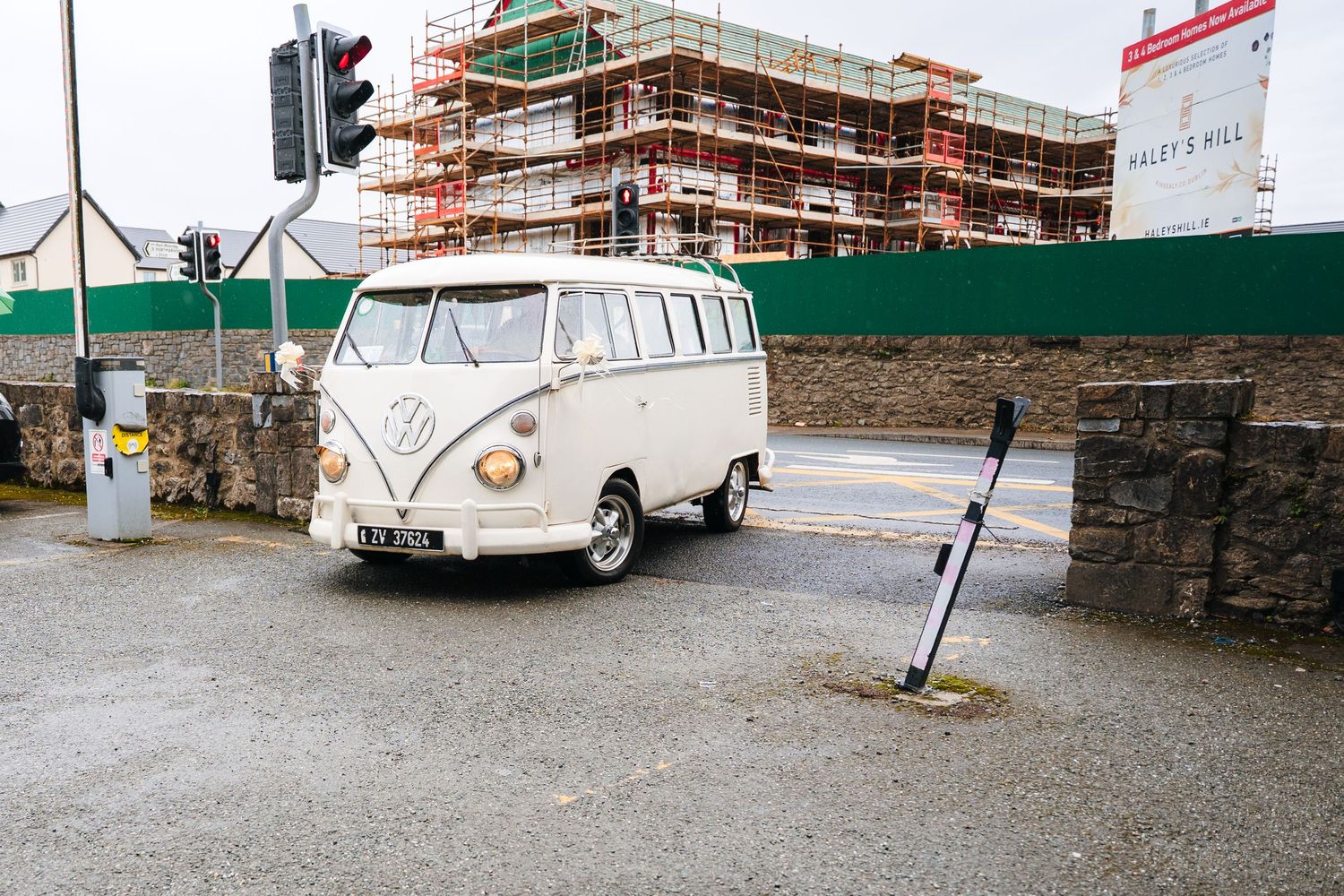 A white vintage ambulance or medical vehicle parked in front of a stone wall and buildings under construction. The Dean Dublin Wedding Photo
