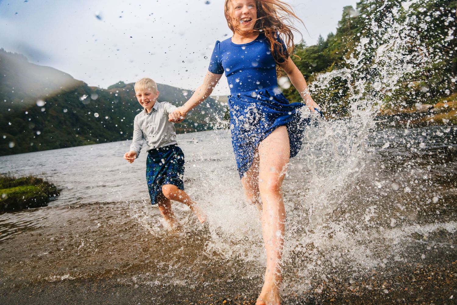 Children running and splashing through shallow water at beach during playtime. Family PHOTOGRAPHER Dublin