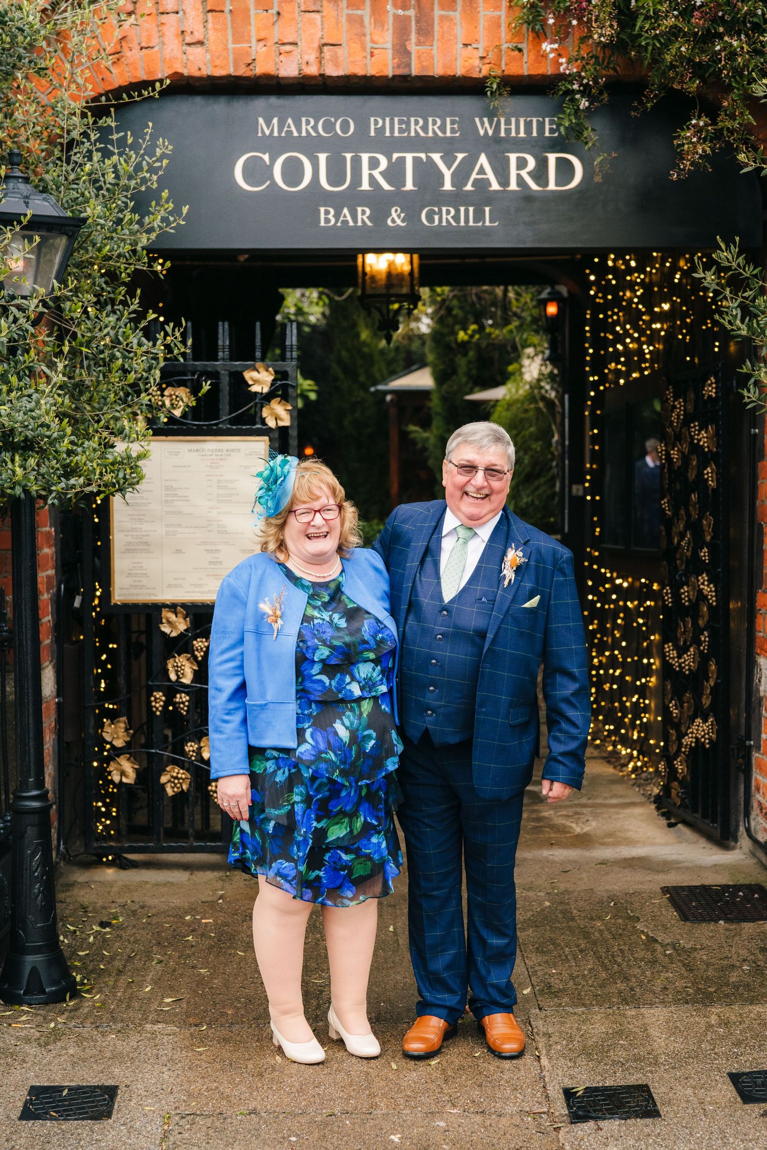 A formal couple poses outside the Courtyard Bar & Grill entrance decorated with twinkle lights. Marco Pierre Dublin Wedding Photographer