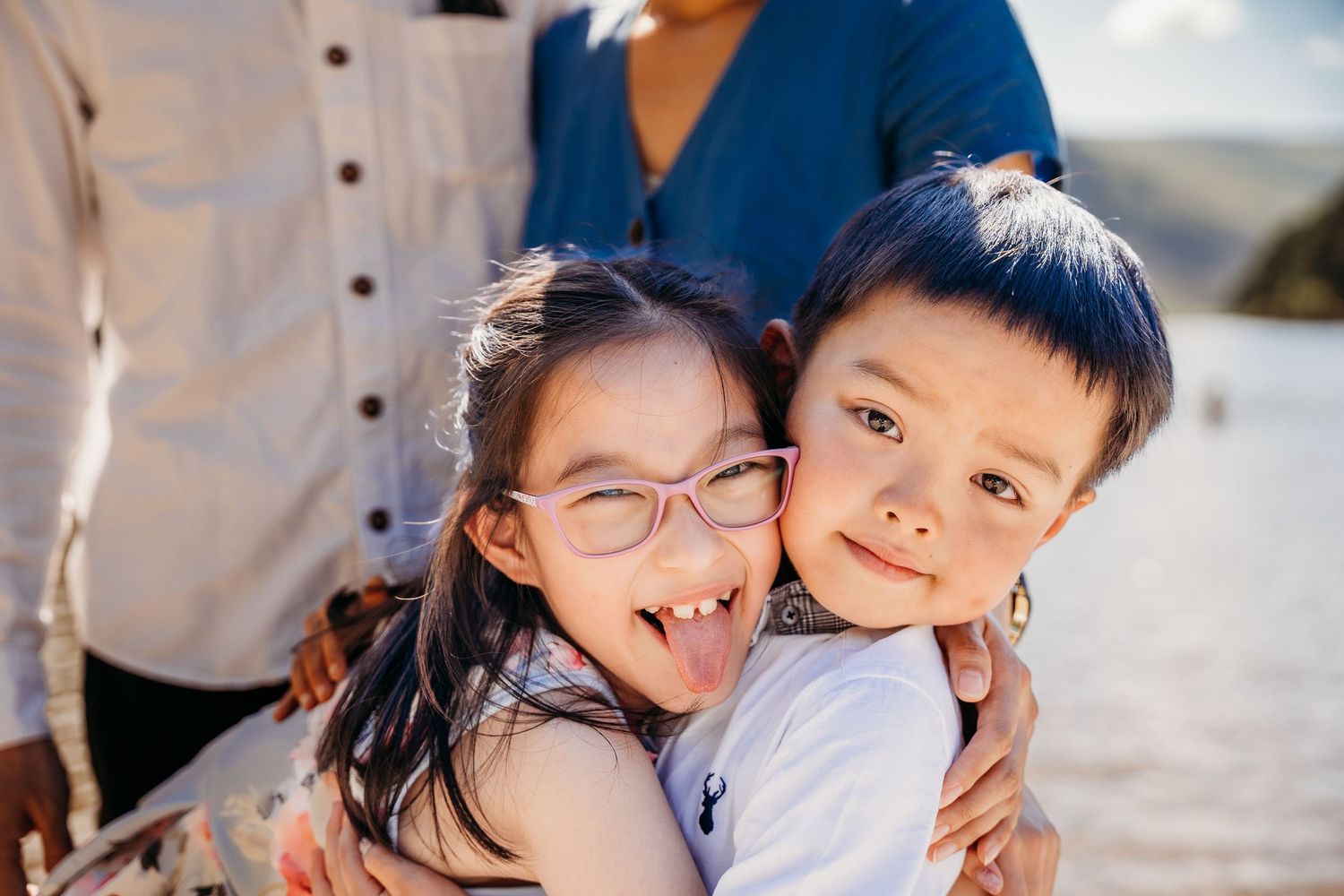 Two young children hugging and smiling outdoors on a sunny day. family PHOTOGRAPHER Dublin