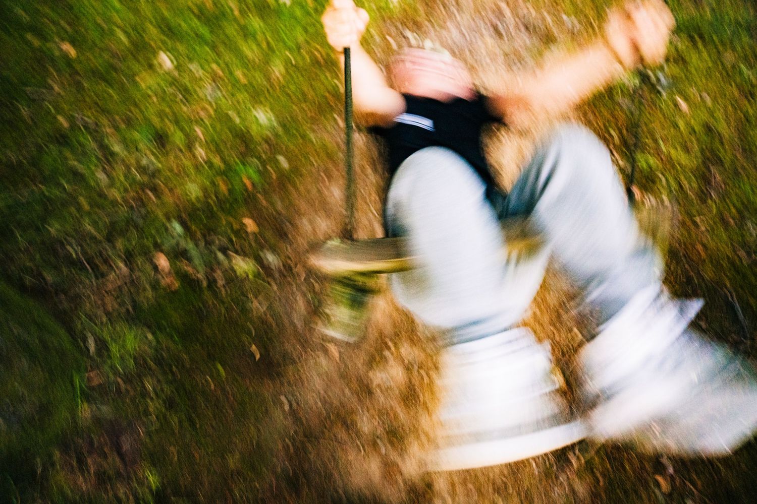 Motion-blurred image of someone swinging on a rope or swing in a grassy outdoor setting. PHOTOGRAPHER Dublin