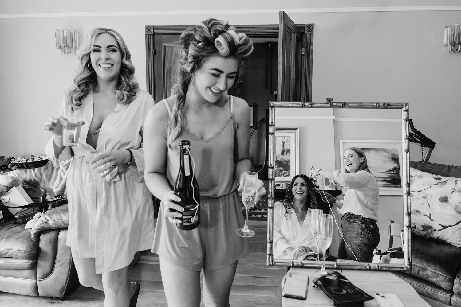 Vintage black and white photograph showing two women in sleepwear getting ready in a bedroom with a mirror reflection. Wedding PHOTOGRAPHER