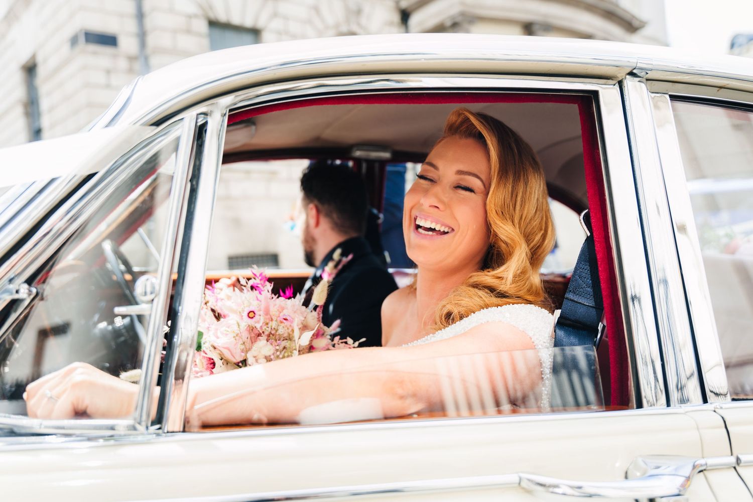 Classic white vintage car with happy passenger smiling inside during a sunny outdoor celebration. Wedding PHOTOGRAPHER Dublin