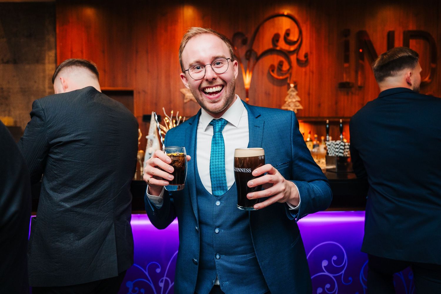 Dimly lit bar scene with purple accent lighting and people enjoying drinks.Wedding photographer dublin
