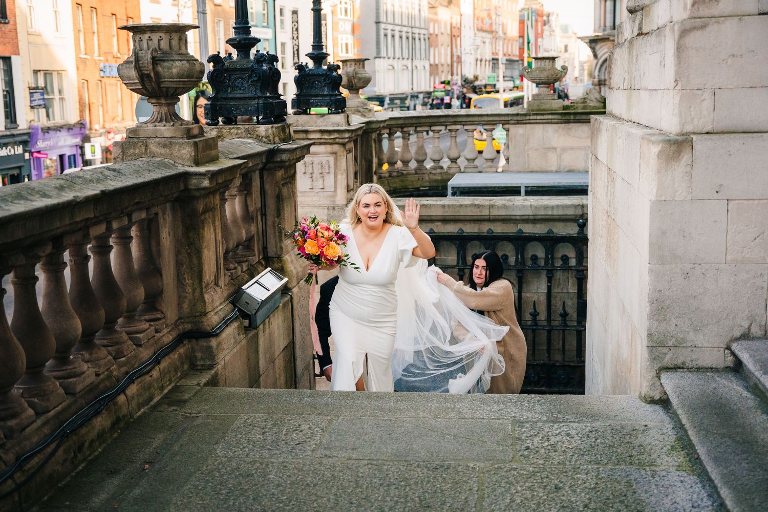 Wedding couple ascending stone steps with ornate architecture and orange bouquet. Wedding photographer dublin