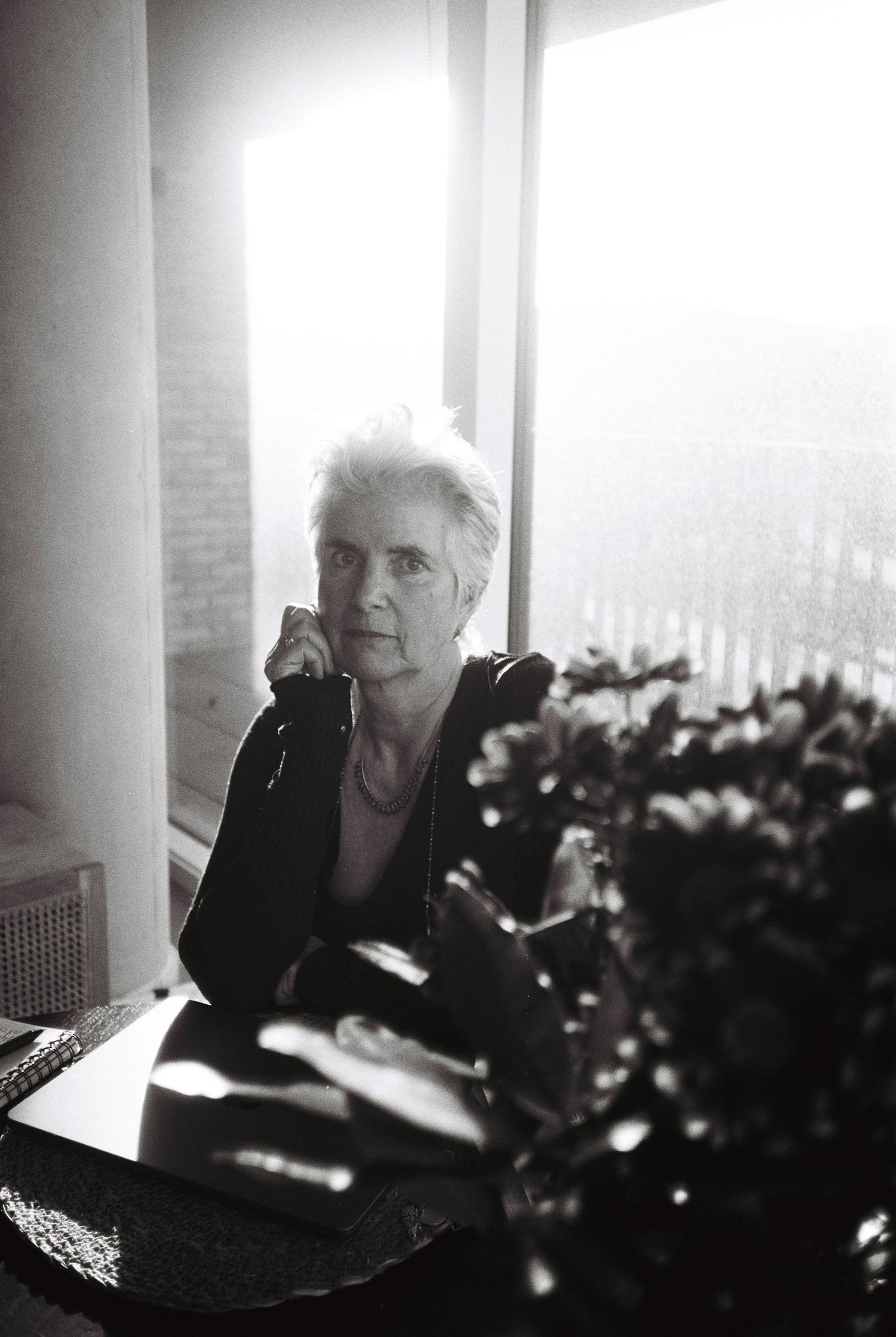 Black and white series of indoor shots showing someone seated by a window with flowers in the foreground. HEADSHOTS DUBLIN