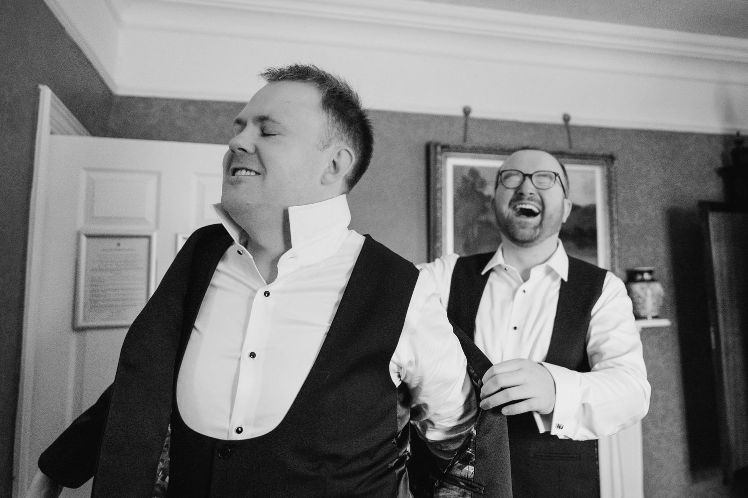 Black and white photo of two people in formal attire laughing together during a candid moment. Wedding photographer dublin