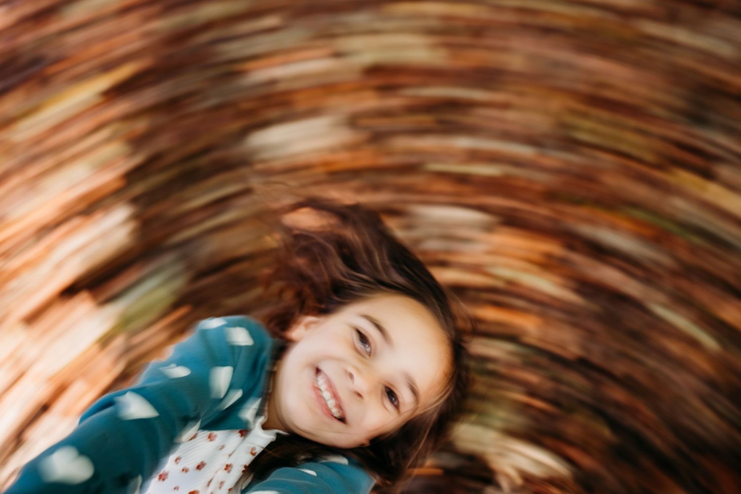 Motion blur swirl effect around someone lying down wearing a teal colored sweater smiling at the camera. family PHOTOGRAPHER Dublin
