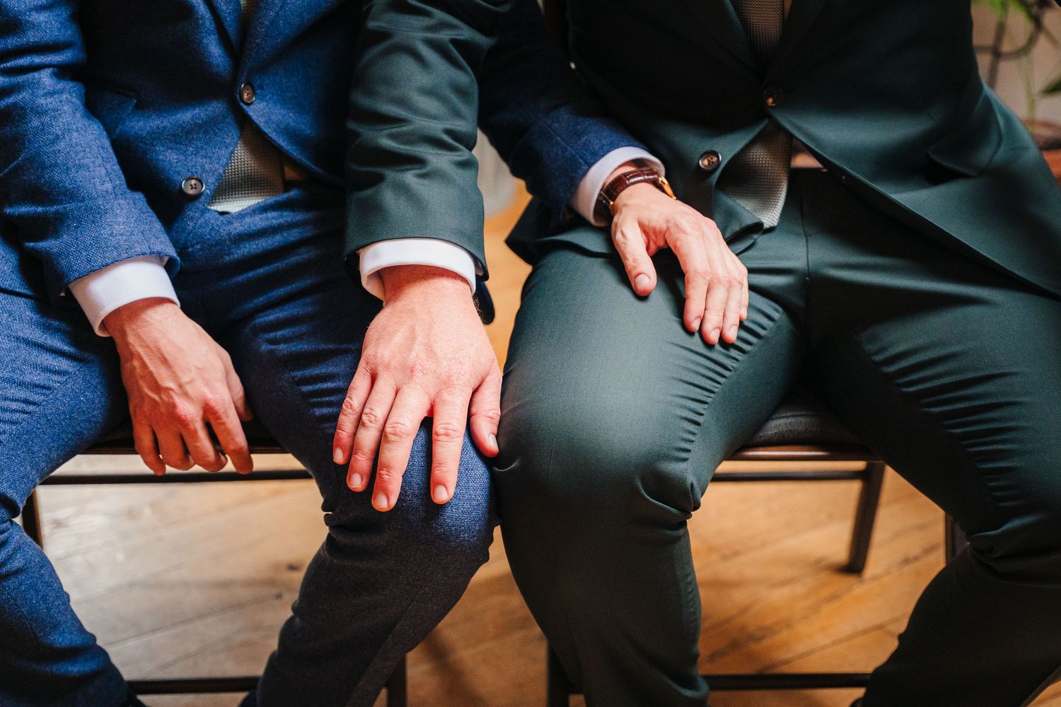 Group of people sitting close together on wooden chairs during an event. Same sex wedding PHOTOGRAPHER Dublin