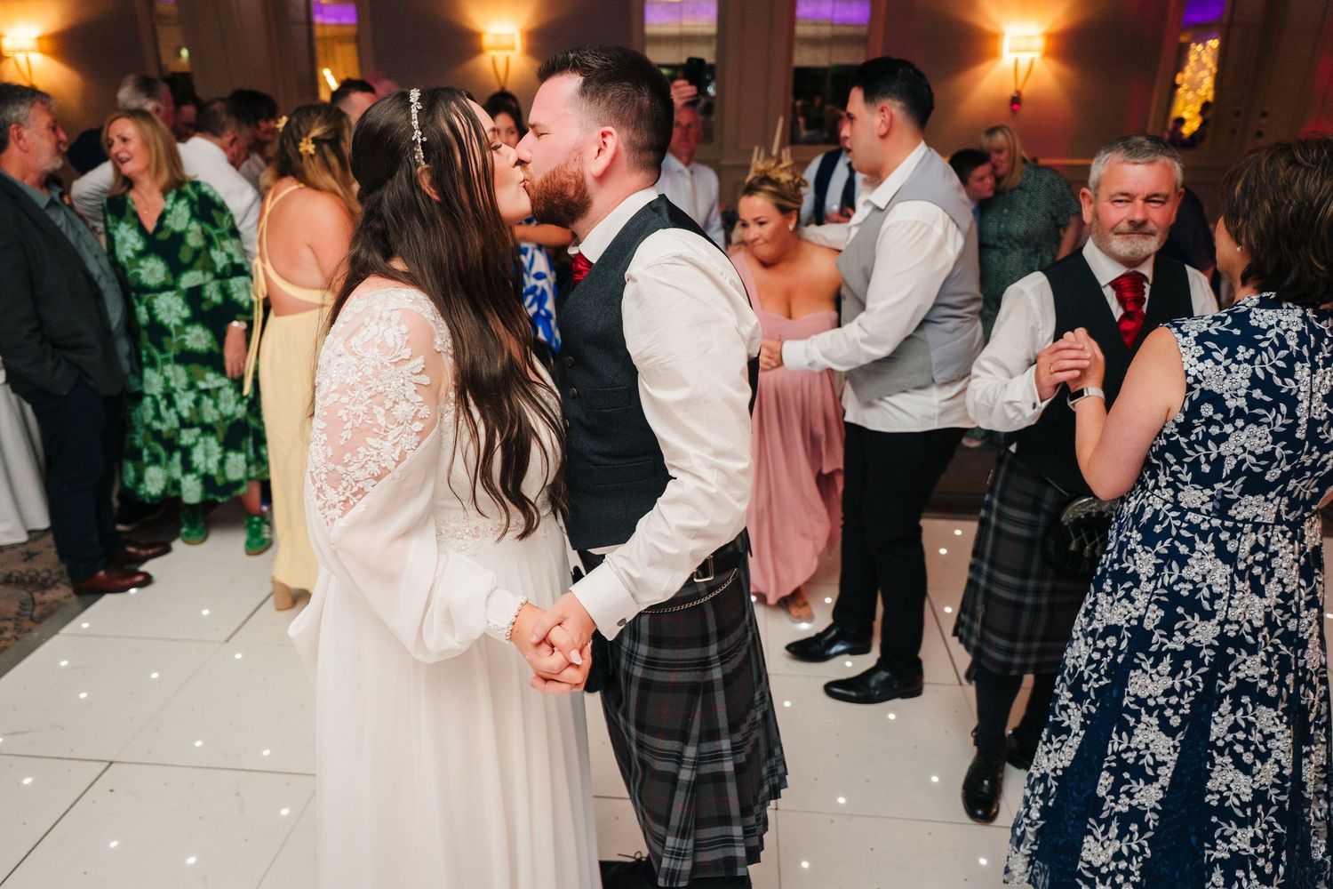 Couples dancing and celebrating at an indoor wedding reception with purple mood lighting. Portmarnock Hotel Wedding PHOTOGRAPHER Dublin