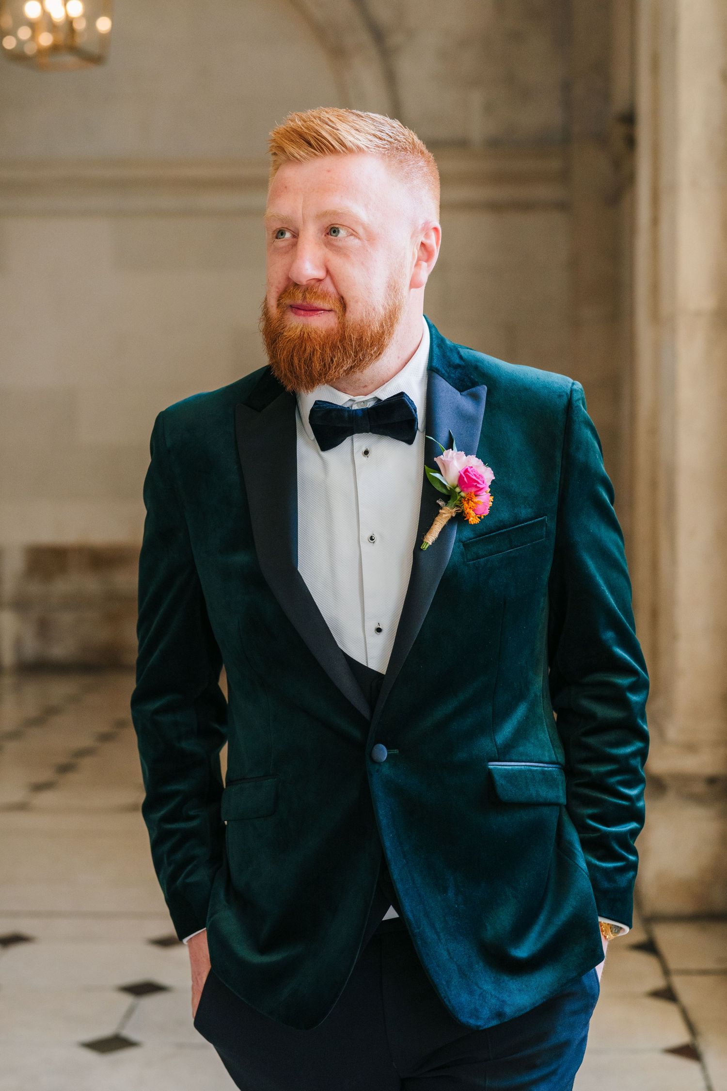 Groom in emerald green velvet tuxedo jacket and black bow tie poses for wedding portraits in an elegant venue. City Hall Dublin Photographer