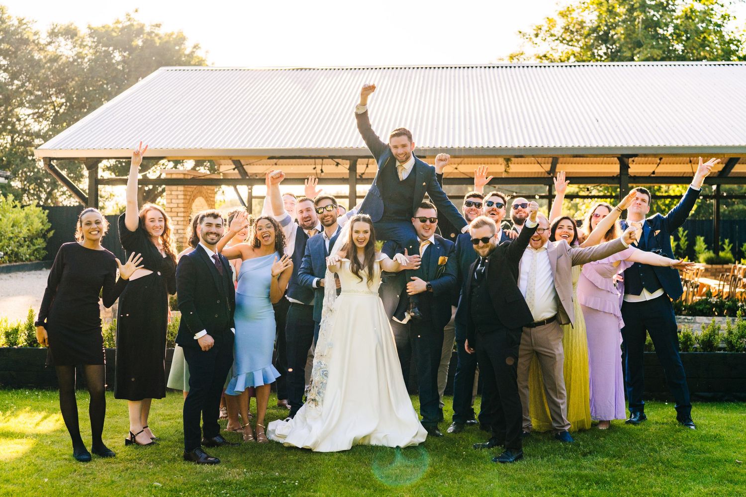 Poulaphouca Wedding photographer wicklow  Wedding guests and newlyweds gather for a celebratory group photo on a sunny outdoor patio.