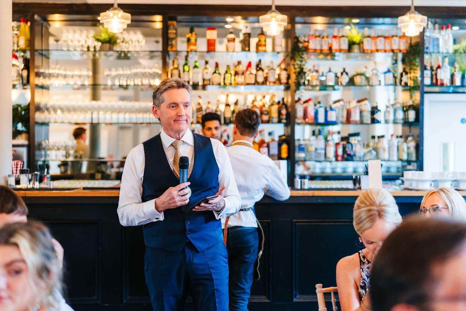 Wedding speech being given at reception with fully stocked bar in background. PHOTOGRAPHER Dublin Ireland Wedding