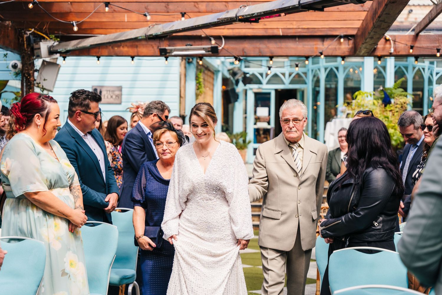 Wedding guests gathered outdoors under wooden beams during a ceremony. House Dublin Wedding Photographer
