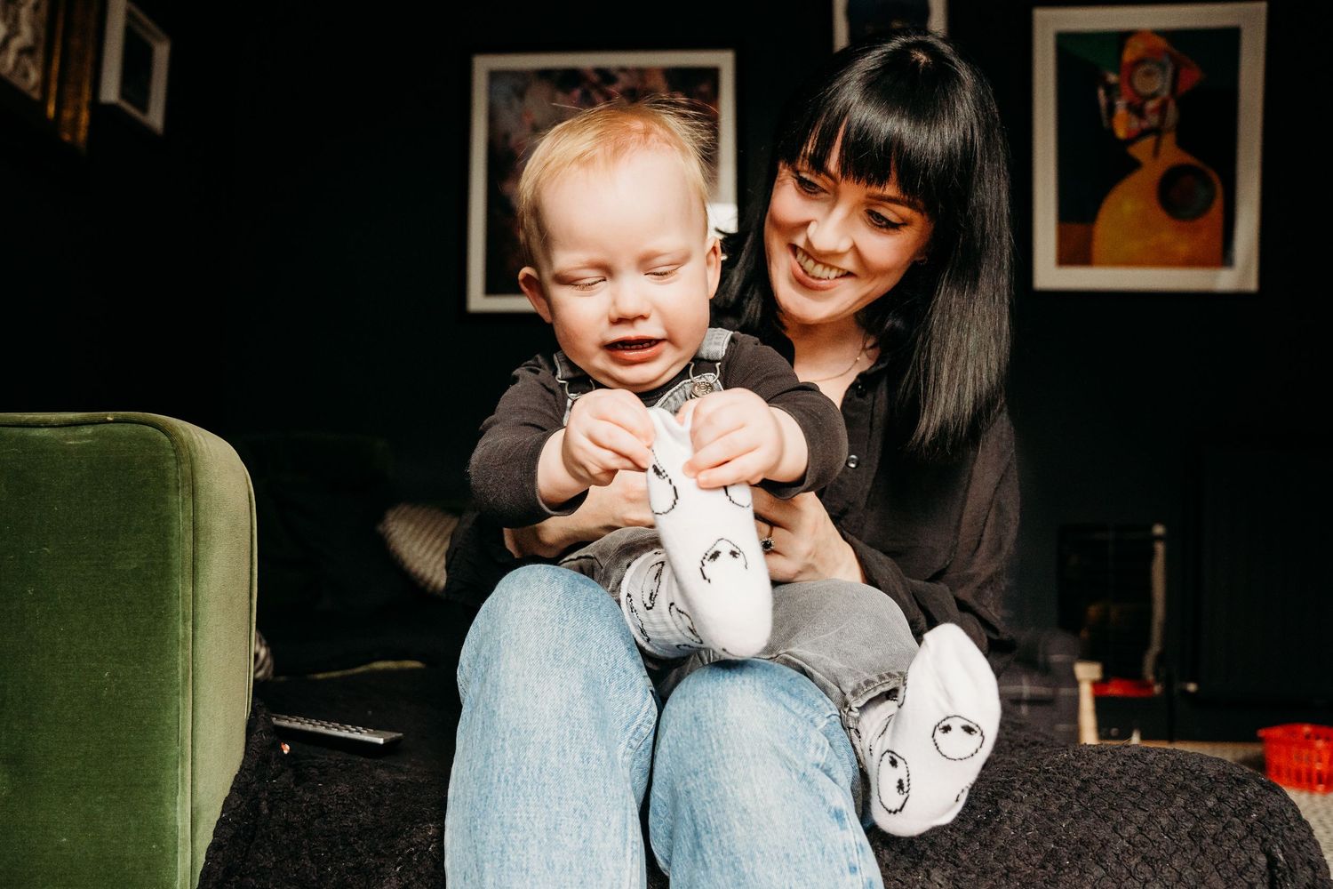 A young child holds up a white ghost sock puppet while sitting with an adult at home. Family PHOTOGRAPHER Dublin