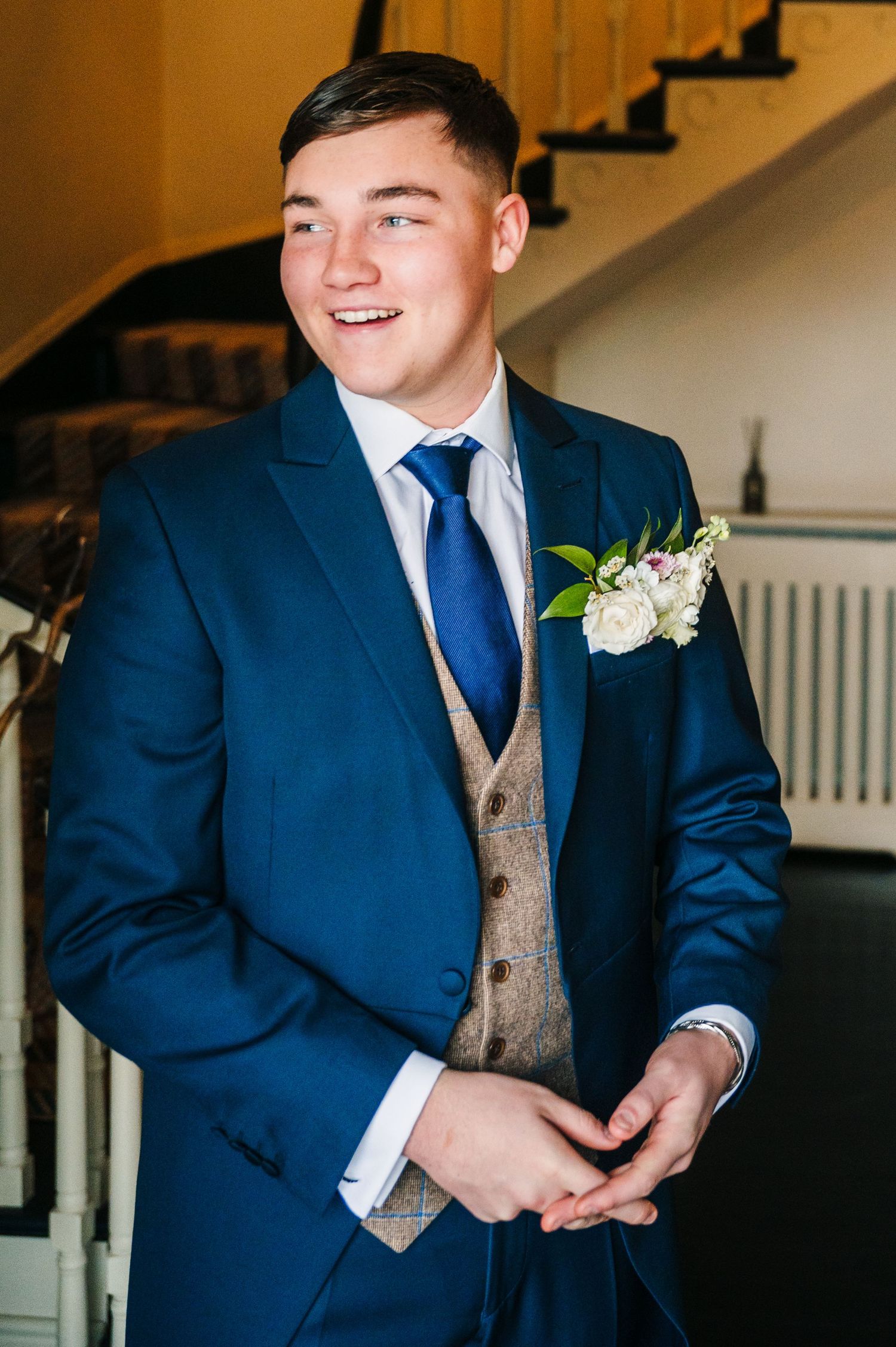 Groom in navy suit and tan vest smiles while getting ready on his wedding day. Virginia Park Lodge Wedding Photographer Dublin Meath Ireland