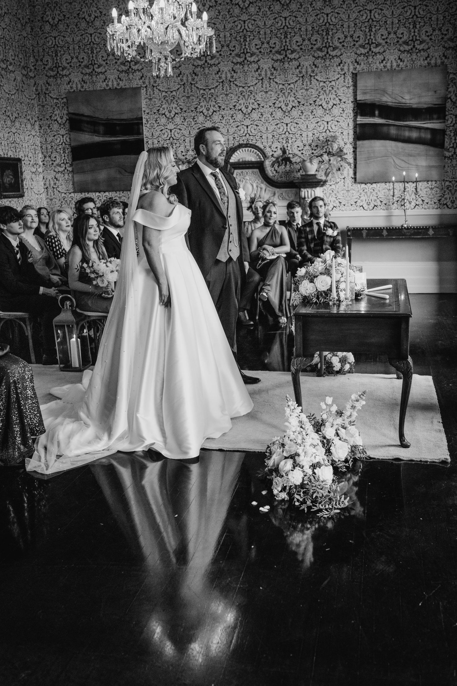 A couple during their first dance in an elegant room with chandelier and floral decorations.  Virginia Park Lodge Wedding Photographer Cavan