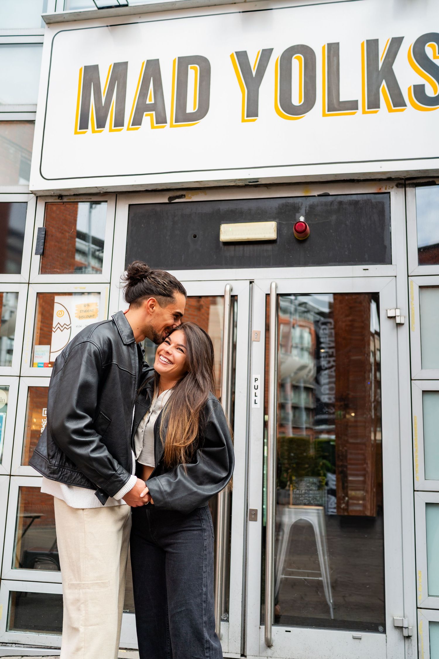 Couple sharing an intimate moment outside Mad Yolks restaurant with storefront signage visible. couple's photographer photoshoot Dublin Irel