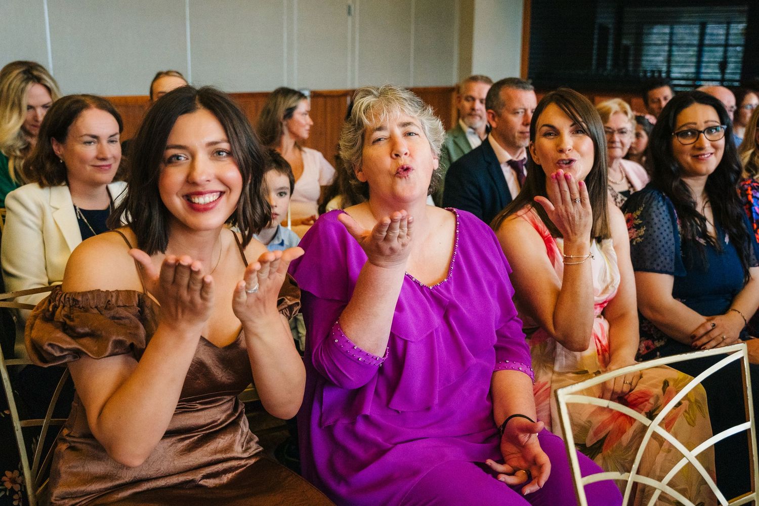 Wedding guests react with excitement and laughter during a celebratory moment at the ceremony. Wedding Photography Trim Castle Ireland