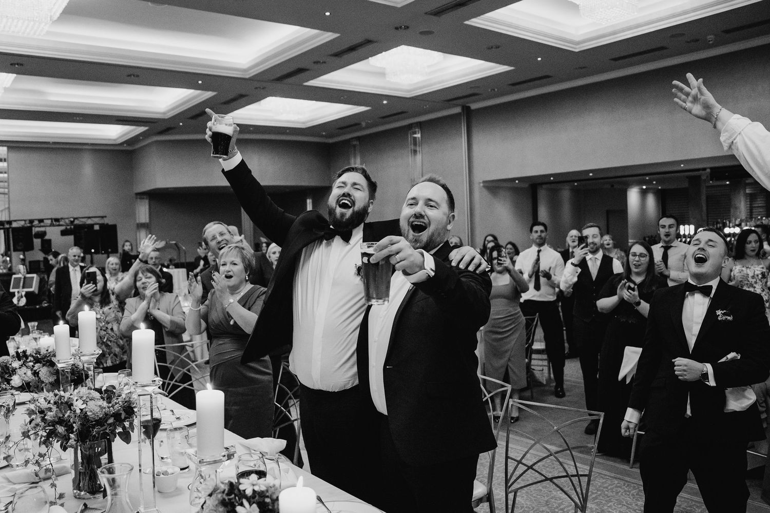 Black and white celebration shot of wedding guests cheering during reception.Wedding Photography Trim Castle Ireland