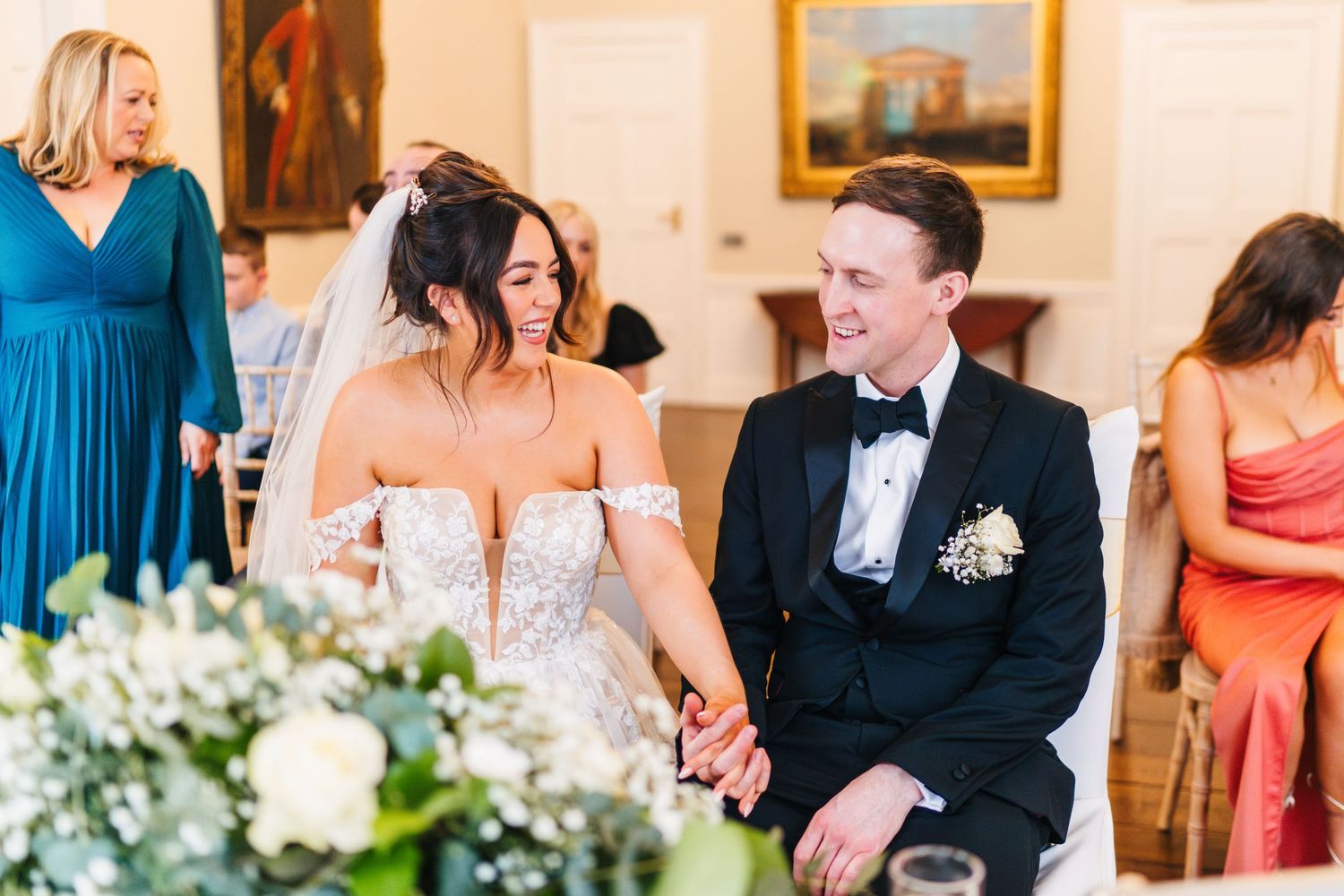 Wedding party in coral and blue dresses pose together in an elegant indoor setting.  Wedding PHOTOGRAPHER Dublin