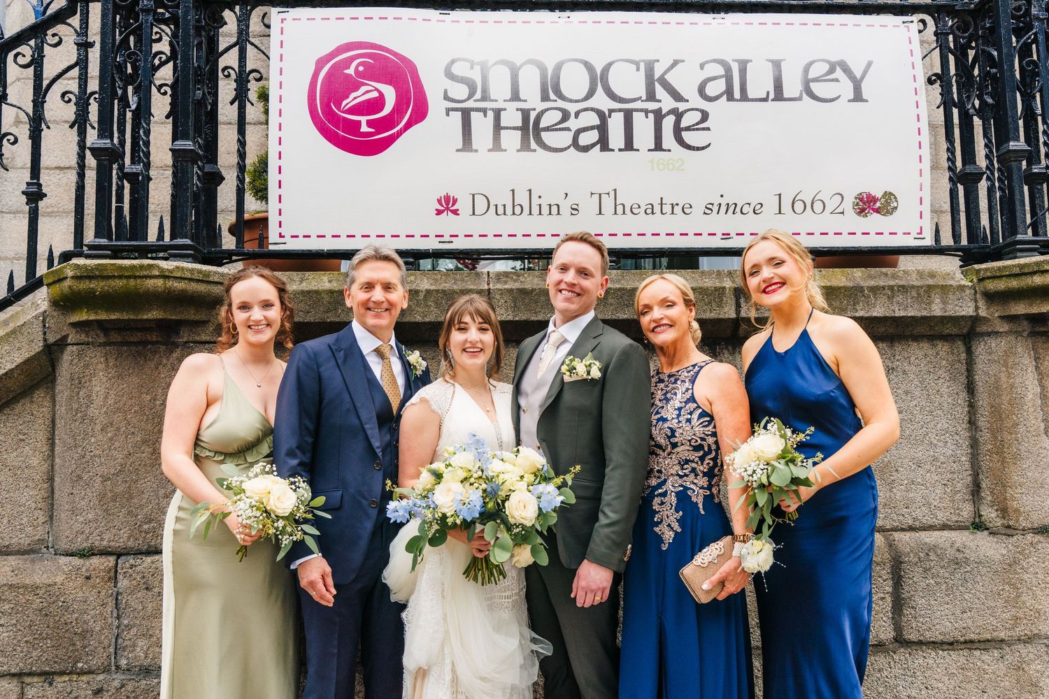 Wedding party poses outside the historic Smock Alley Theatre entrance with stone pillars. PHOTOGRAPHER Dublin Ireland Wedding