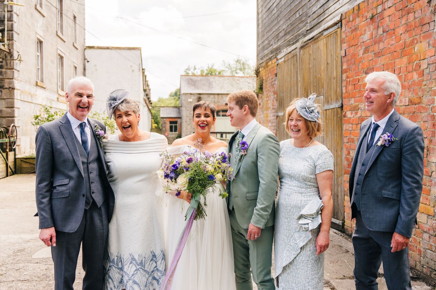 Millhouse slane wedding photographer dublin Wedding party gathered outside brick building in formal attire.