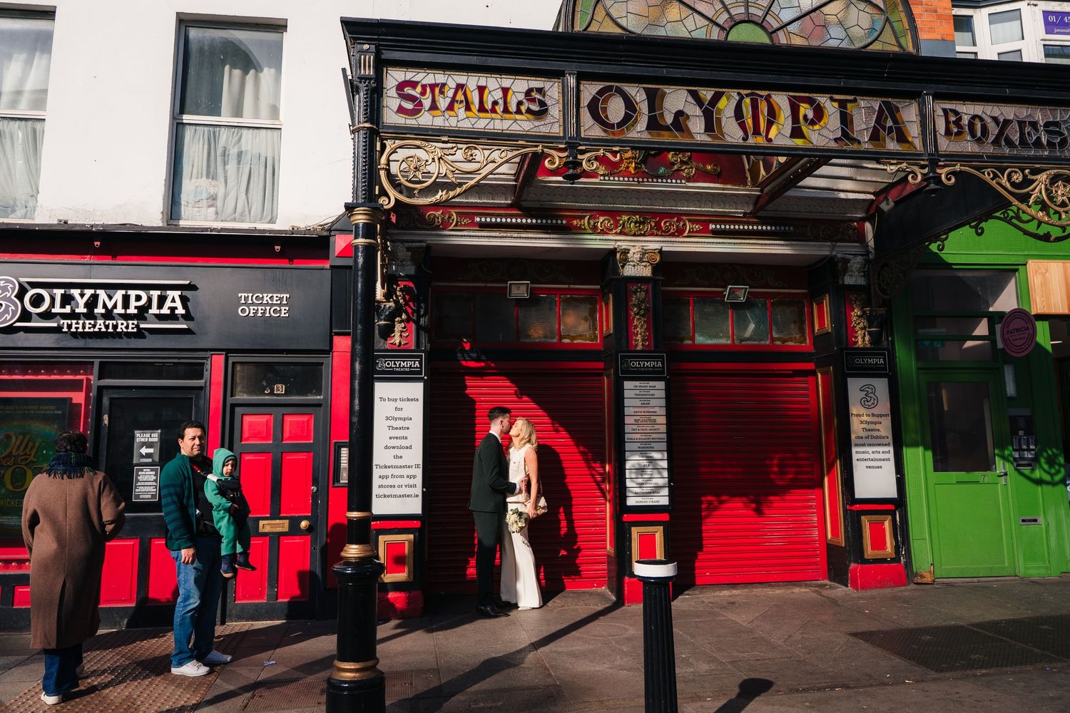 Wedding couple posing outside historic Olympia Theater with red facade and vintage signage. City Hall Dublin wedding photogrAPher