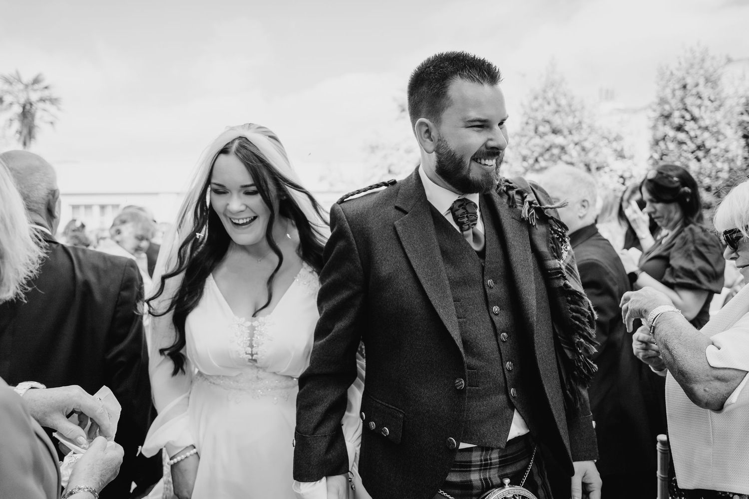 A joyful couple shares a candid moment during their wedding celebration outdoors. Portmarnock Hotel Wedding PHOTOGRAPHER Dublin