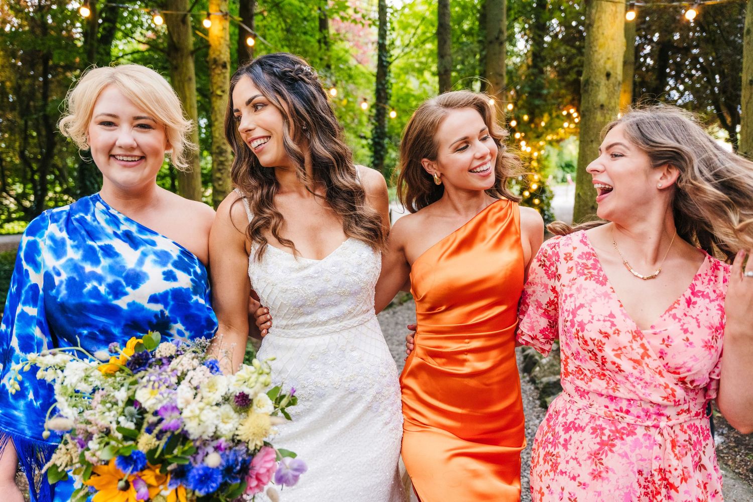 A group in colorful attire shares joyful laughter while posing together outdoors in natural lighting. Wedding PHOTOGRAPHER Dublin