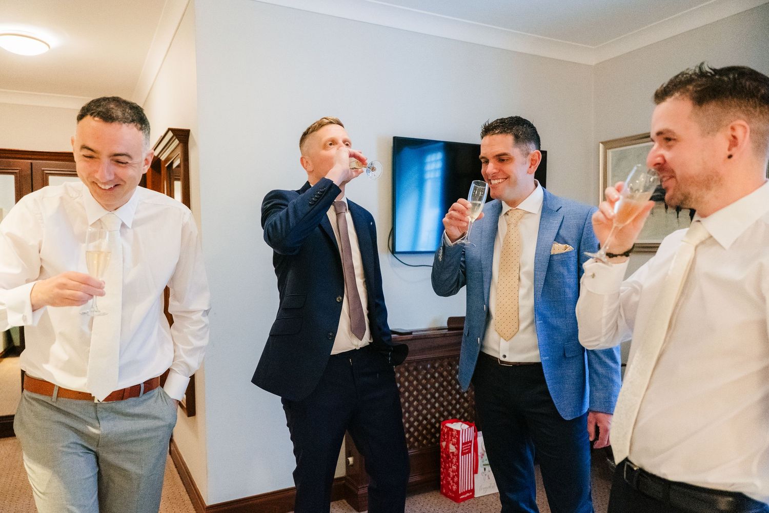 Groomsmen share a lighthearted moment getting ready in a bright hotel room before the ceremony. Marco Pierre Dublin Wedding Photographer